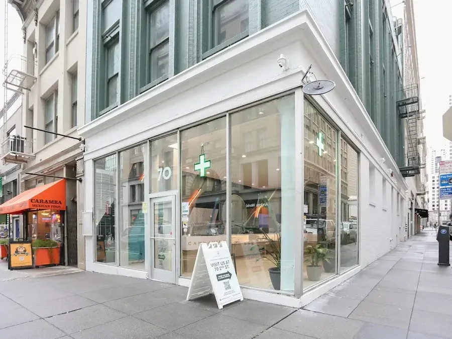 Corner storefront with glass windows and green cross sign, urban street view