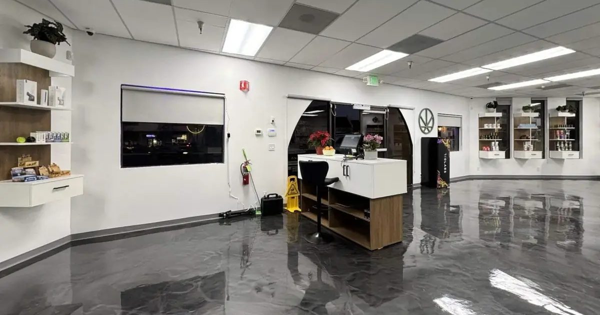 Spacious dispensary interior with polished floors, white counter, and wall displays
